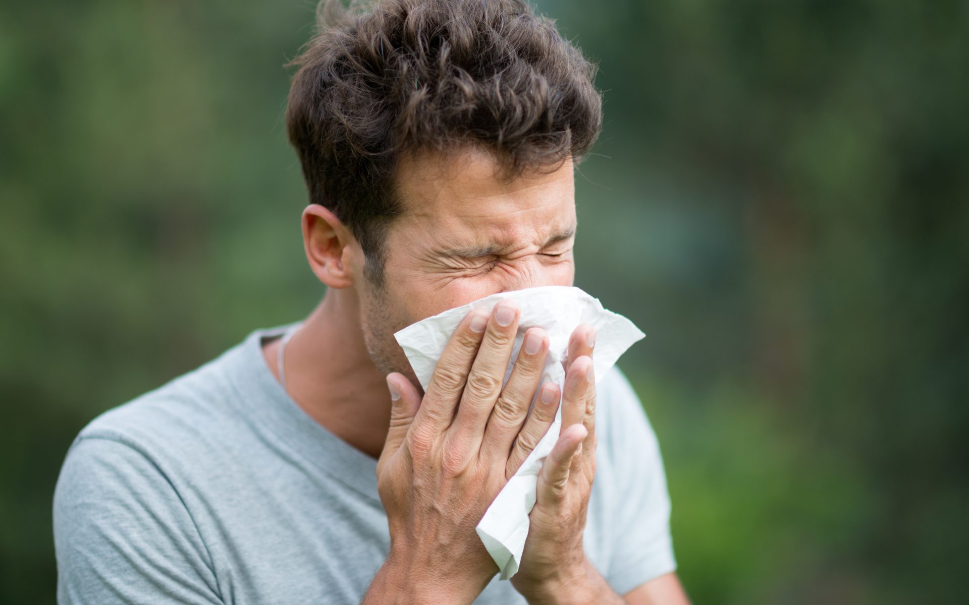 man blows nose into tissue