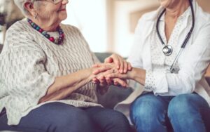 a doctor holds a concerned patients hand to comfort them